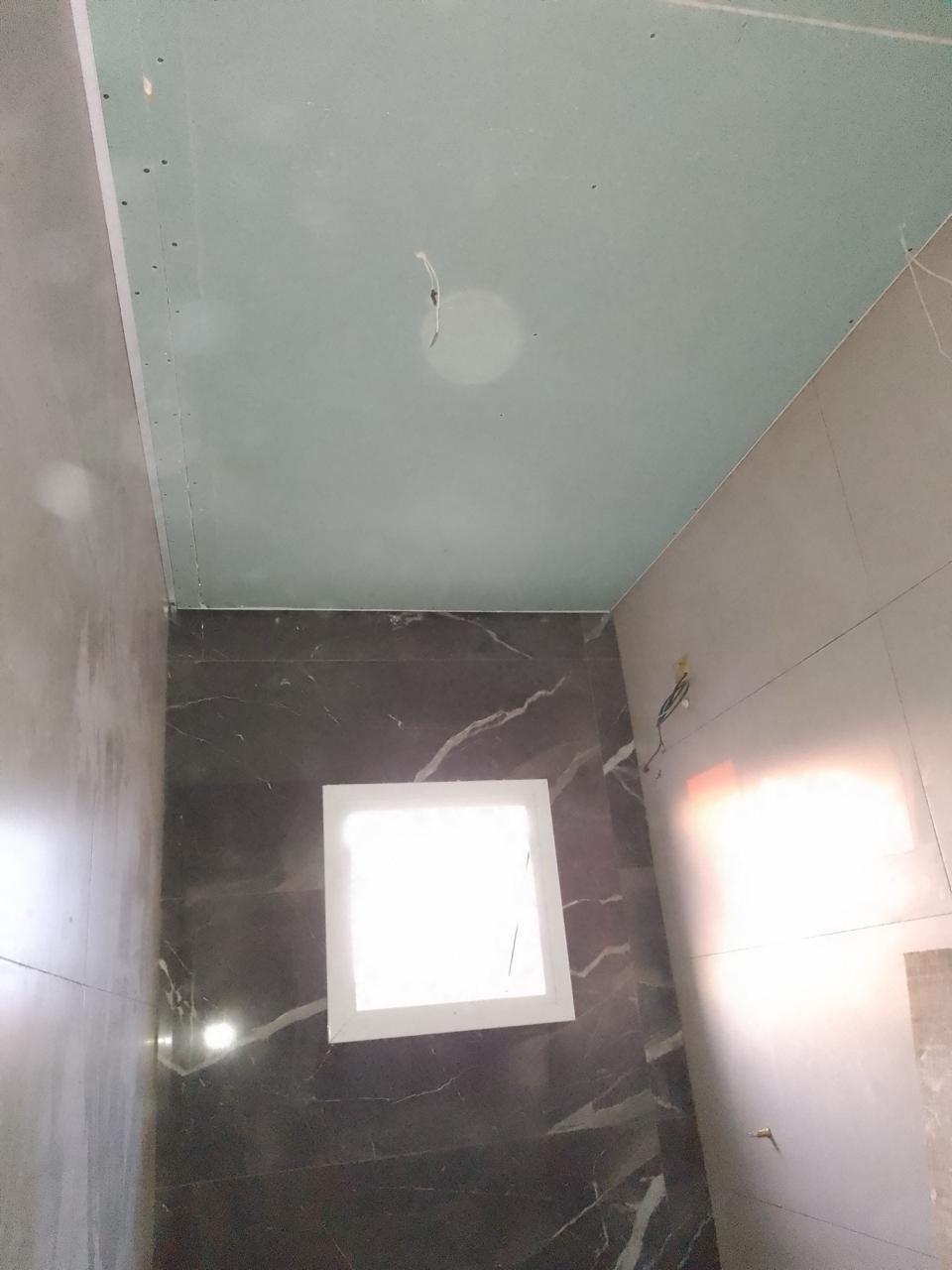 interior de uma área com teto em gesso branco e piso de mármore preto com janela em forma de quadrado branco n
