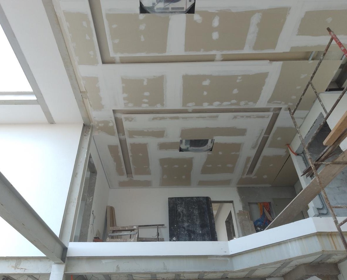 interior de construção com teto em gesso, escada de madeira e materiais de obra  — texto:  
